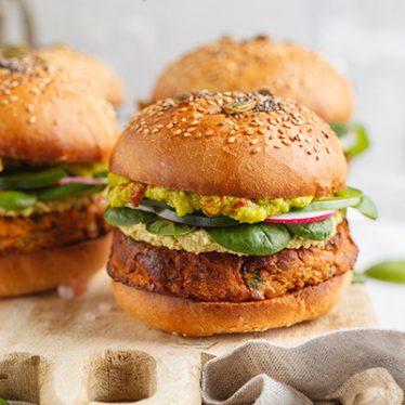 baked sweet potato burger with whole grain bun, guacamole, vegan mayonnaise and vegetables