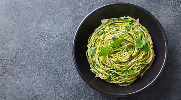 spaghetti pasta with fresh pesto sauce and basil leaves